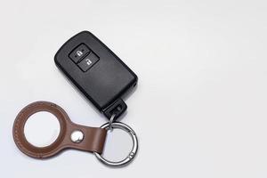 Bangkok, Thailand - April 14 2023 Modern black remote control of car and Apple Air Tag with brown leather keychain  isolated on white background with free space for adding some text on the right photo