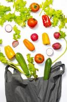 Flat lay composition with fresh ripe vegetables and bag on white background. Flat lay set of seasonal vegetables and bag on a white background. Frame of various vegetables and bag on background photo
