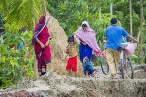 Bangladesh June 27, 2015 Man woman and peoples are crossing river erosion affected roadside at Rasulpur, Barisal District. photo
