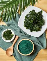 Top view laminaria or kelp seaweed and spirulina powder in wood bowl and spoon background. flat lay spirulina powder with konbu and alga food on wood table background photo