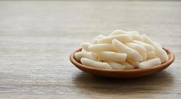 Tteok or Korean Rice Cakes in a wooden plate on wood table background photo