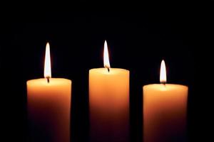 Flame candles with decorative lights on black table background photo