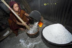 Bangladesh February 09, 2018 An elderly village woman prepares khoi puffed rice from Binni Dhan husk glutinous rice as Bengalis traditional festivals meals at savar, Dhaka. photo