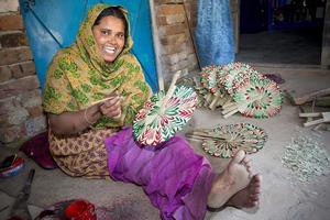 Bangladesh febrero 15, 2018 un mujer artesano es colorante un tradicional hecho a mano palma hoja ventilador con un color Cepillo de pintura a bogura, bangladesh foto