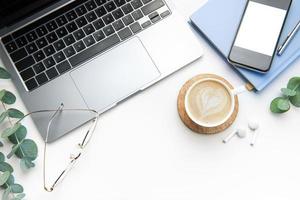 Office desk table with laptop, supplies and coffee cup photo