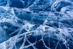 Natural texture of transparent clear ice of a lake with cracks. Many cracks in thick ice. Horizontal. photo