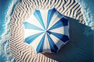 blue and white umbrella sitting on top of a sandy beach. . photo