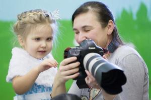 The photographer shows the camera to a little girl. Children's photographer. photo