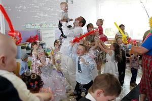 . divertido fiesta con niños y padres con globos y jabón burbujas foto