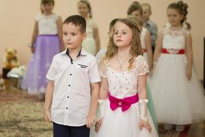 . vestido arriba chico y niña son preescolares niños realizar en jardín de infancia. foto