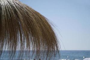 Straw Umbrella on a Beach, Sea on Second Plan photo