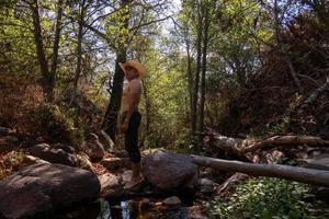 Shirtless cowboy man in creek with trees photo