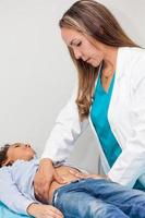 Doctor examining and performing the technique of abdominal percussion to a child photo