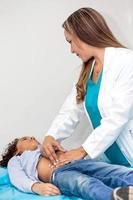 Doctor examining and performing the technique of abdominal percussion to a child photo