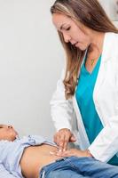 Doctor examining and performing the technique of abdominal percussion to a child photo