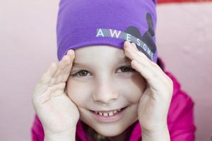 retrato de un alegre preescolar niña en un púrpura sombrero. foto