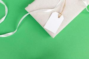 White empty tag on clothes. Mockup of a price tag label on a fabric product. Green background photo