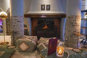 Book with decor on table and empty ottomans by fireplace in hotel room photo