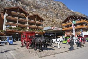 Tourists looking at horse cart outside building against mountain photo
