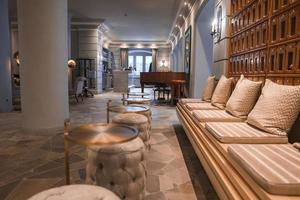 Cushions arranged on empty sofa with ottomans in hotel lobby photo