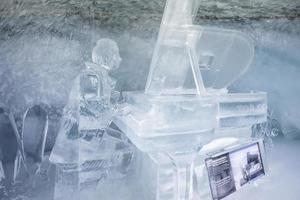 Ice statue of man playing piano in glacier tunnel inside ice palace photo