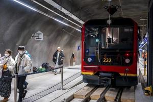 Passengers walking at platform by red train in mountain tunnel photo