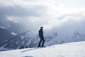 Tourist skiing on peak of snow covered mountain on vacation photo