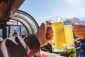 Tourists toasting beer glasses at ski resort during vacation photo