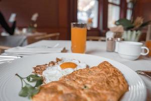 Sunny side up egg and omelet with juice on dining table at restaurant photo