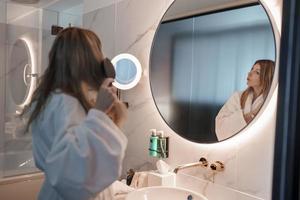 Blond woman brushing her hair in bathroom at luxury hotel photo