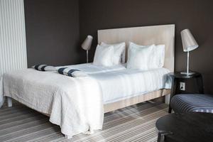 Pillows and cushions on bed with lamps on night tables in bedroom photo