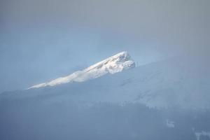 Beautiful view of snow covered Bernese alps during foggy weather photo