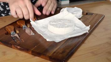 fechar-se. mulheres mãos cortar queijo Camembert com uma pequeno faca. video