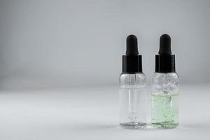 two glass bottles of cosmetic serum on a light background photo