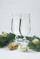 nuevo años foto, corcho desde champán y bozal, ramas de un familia árbol, dorado Navidad pelotas y lentes de champán foto