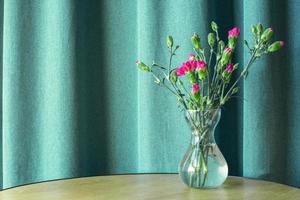 Vase with pink flowers on a table on a blue background. Carnations. photo
