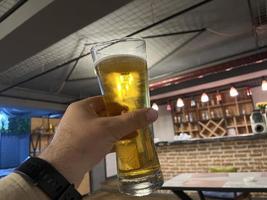 del hombre mano participación un cerveza vaso en un pub o restaurante. foto