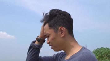 jung Mann Indonesien Stress und Depression Ausdruck auf Tag Licht mit Natur Himmel Hintergrund. das Aufnahmen ist geeignet zu verwenden zum Werbung und Ausdruck Inhalt Medien. video