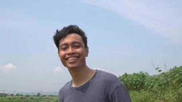 joven hombre Indonesia animar y sonrisa expresión en día ligero con naturaleza cielo antecedentes. el imágenes es adecuado a utilizar para publicidad y expresión contenido medios de comunicación. video