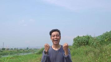 Young man Indonesia cheer and smile expression on day light with nature sky background. The footage is suitable to use for advertising and expression content media. video