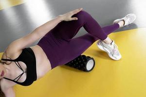 a young girl athlete rolls out the side of the thigh on a foamroller. Myofascial release photo