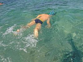 chico buceo en el mar en azul agua en un verano calentar fiesta día foto