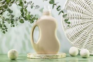 Bottle of washing gel on wooden podium with laundry balls photo