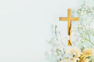 Wooden cross with spring flowers on blue background with copy space photo