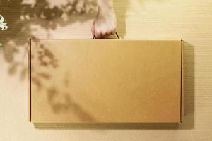 Cardboard box in delivery man hand on cardboard background photo