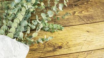 Bouquet with eucalyptus branches on wooden background with copy space photo