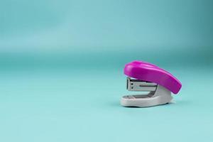 gray-pink stapler on a blue background. Bright stationery photo