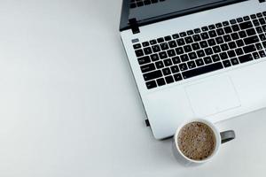 White laptop with a cup of cocoa on a white background. Laptop with black keyboard. photo