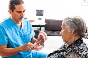 Senior woman patient looking at a dental model while the dentist explains her the correct way to brush her teeth photo