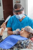 Male middle -aged dentist at his office with a senior woman patient photo